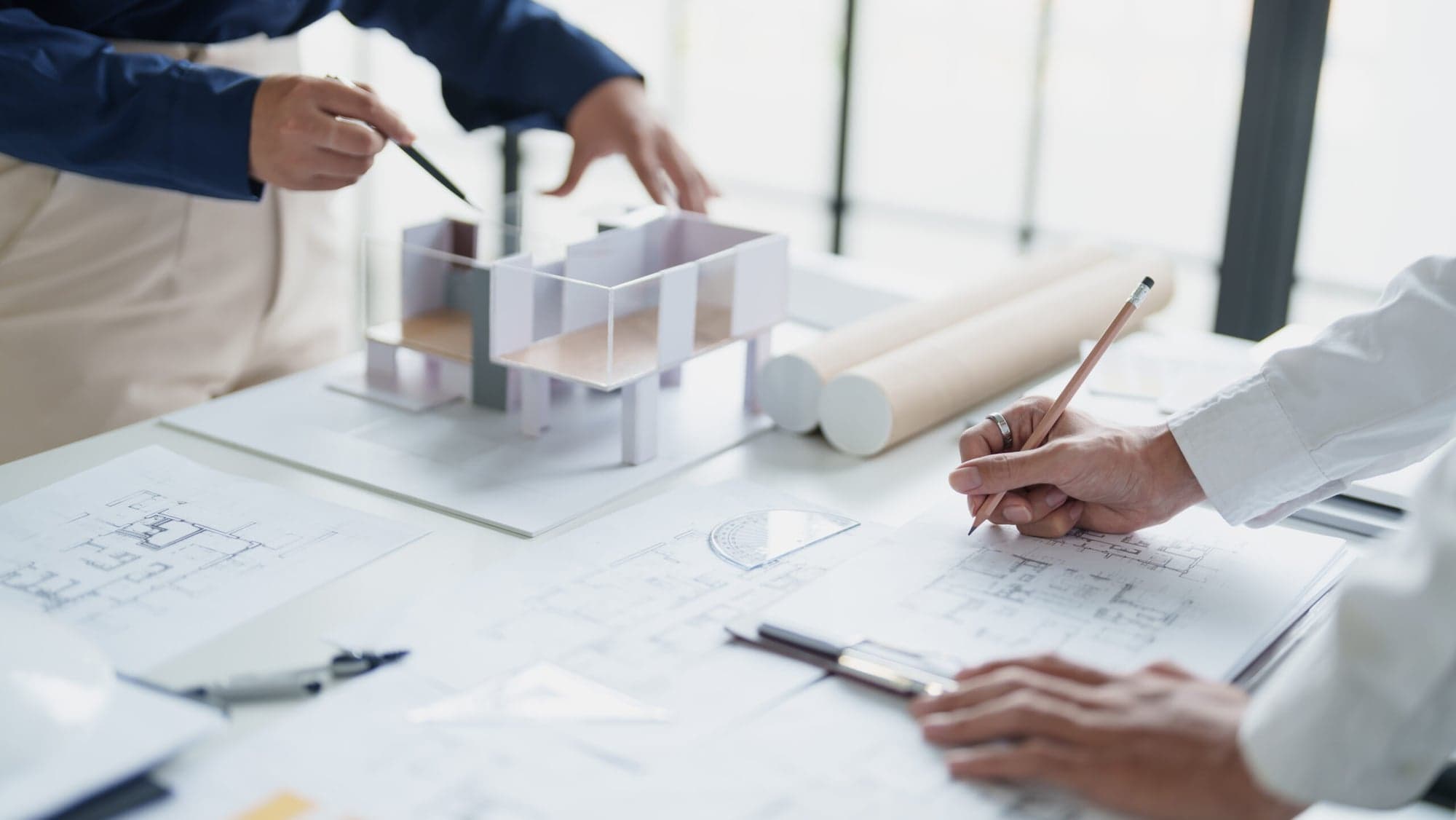Architekt arbeitet an Architekturmodell mit Stift und Plänen – Konzept und Entwurf fbnSTUDIO